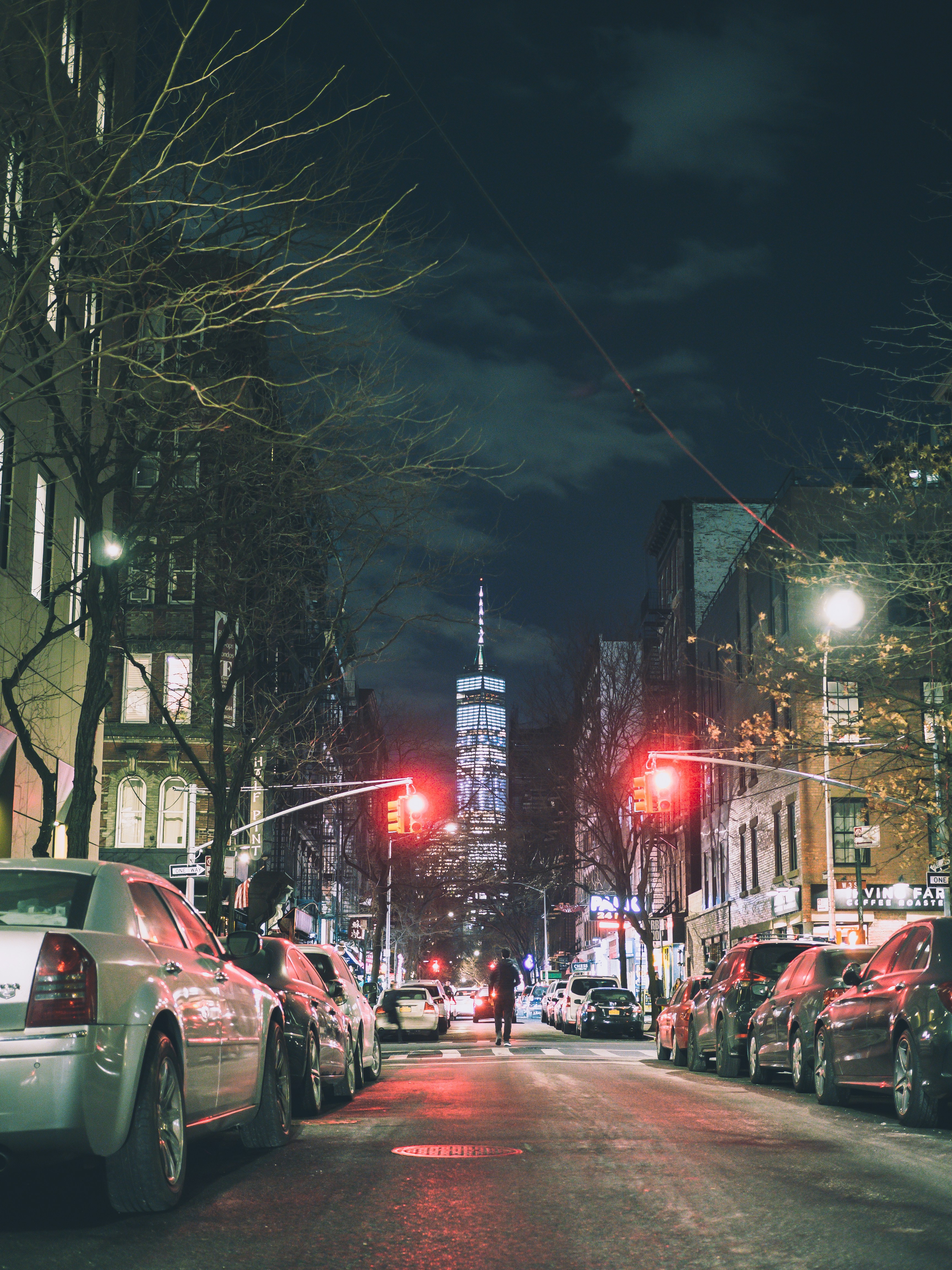 person walking on street between parked vehicles during nighttime