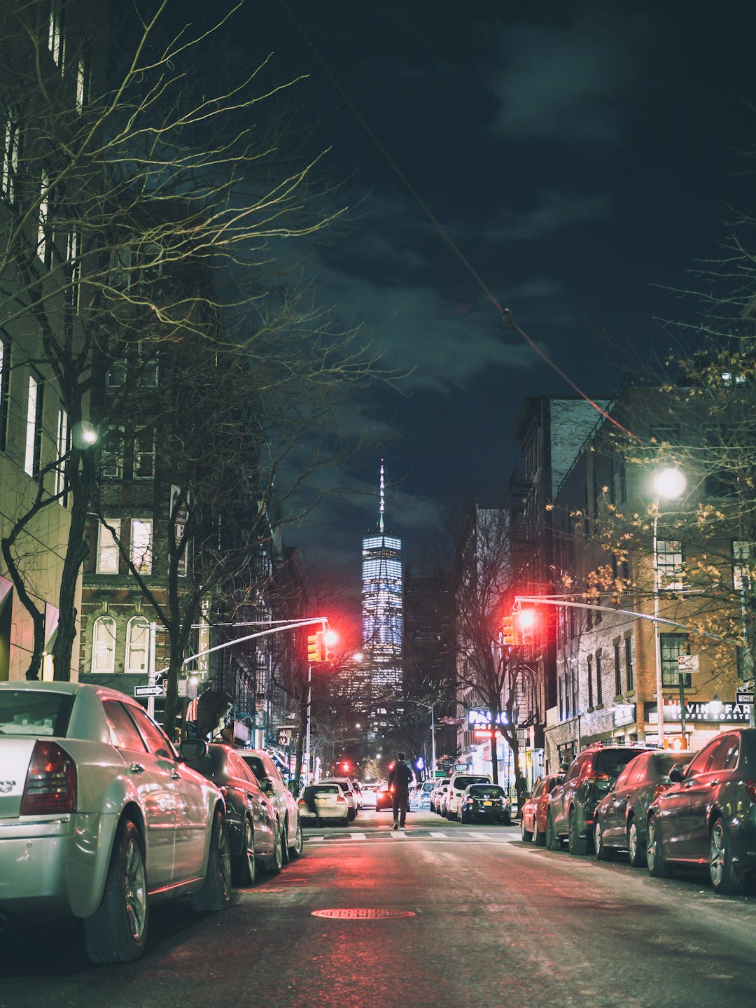 person walking on street between parked vehicles during nighttime