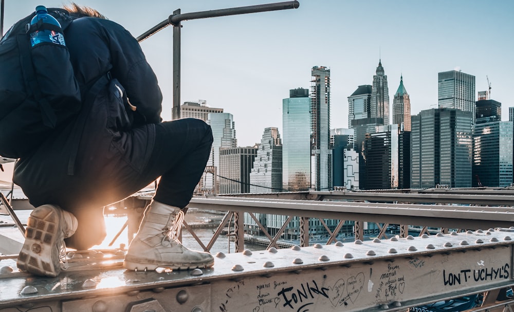 man sitting on gray scaffolding taking photo