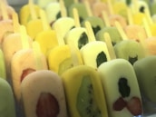 Rows of vibrant long ice pops lined up with fresh fruit pieces inside