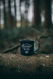 teal and white cup on brown tree log