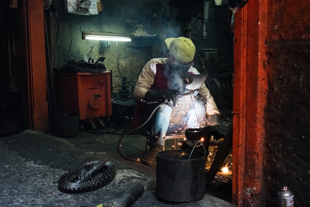 man welding an item inside room