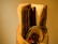 A collection of dark wooden chopsticks, a metal spoon, and folded napkins arranged in a holder with a warm, yellowish background.