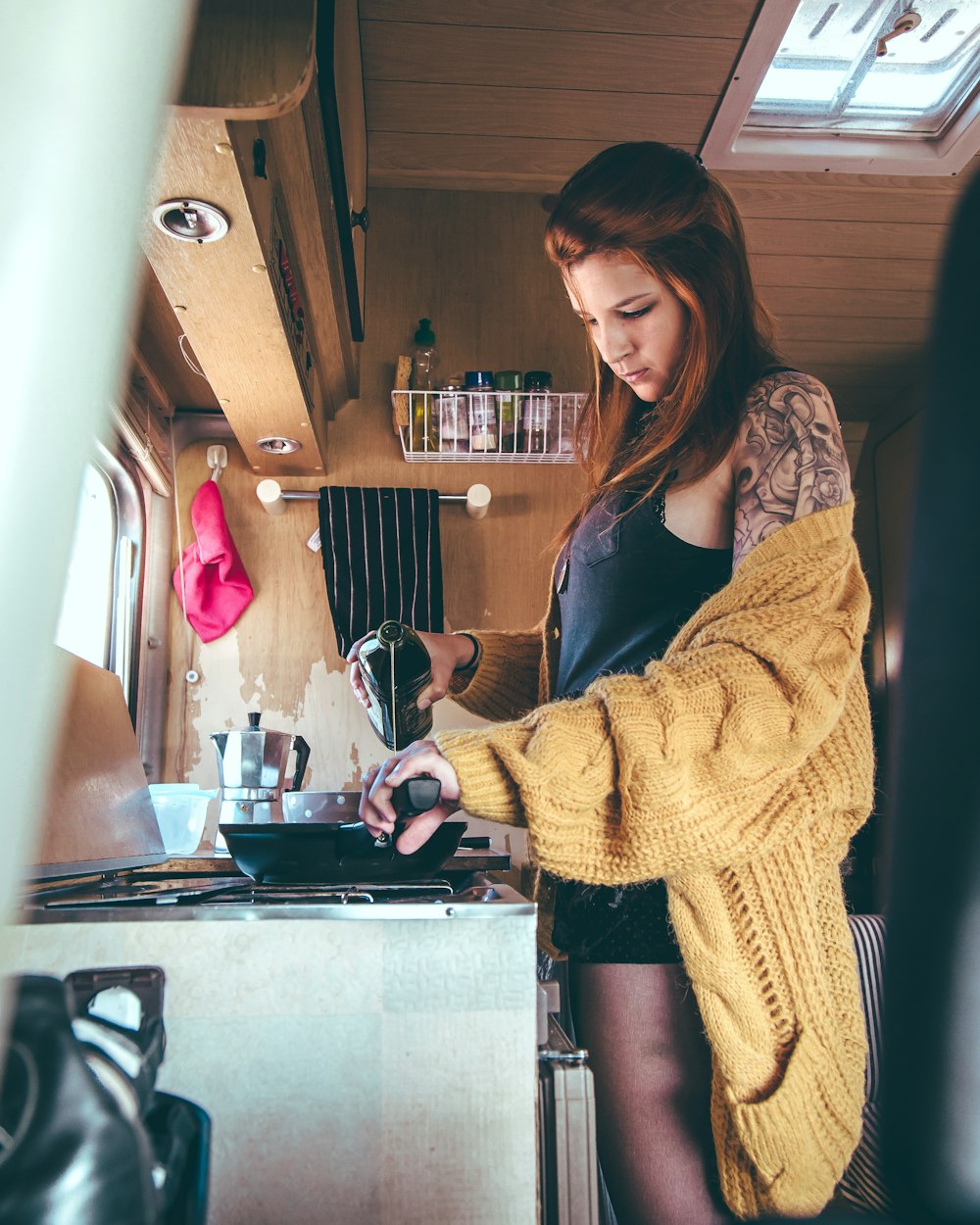 girl wearing yellow knitted sweater holding glass bottle and fry pan