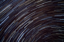 Long exposure photograph capturing the circular trails of stars in the night sky, creating a mesmerizing pattern against a dark background.