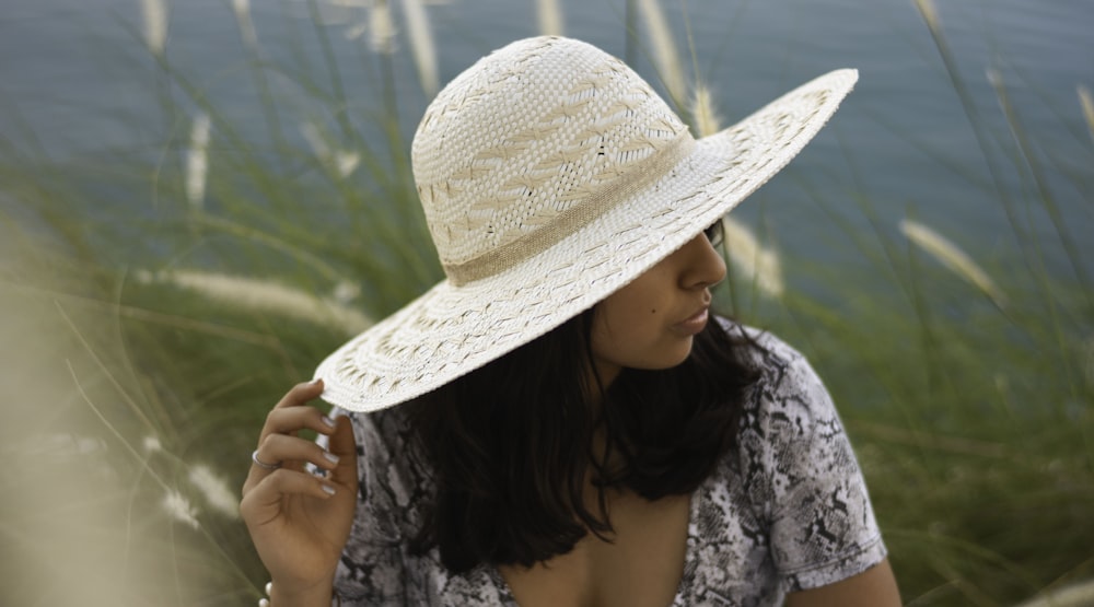 woman wearing white and black floral top holding brown straw hat