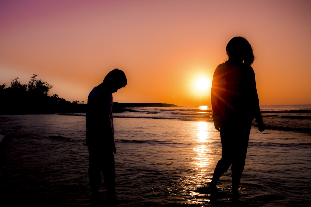 silhouette photography of boy and girl standing at beach