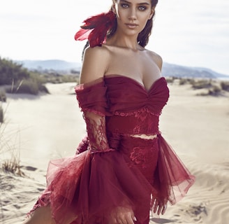 woman wearing red dress kneeling on sand