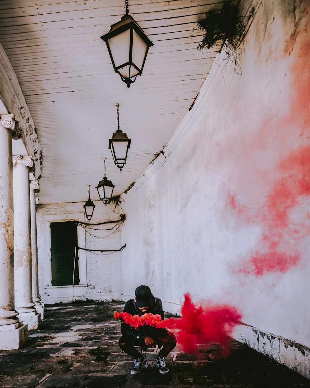 man holding flare smoke near white painted wall