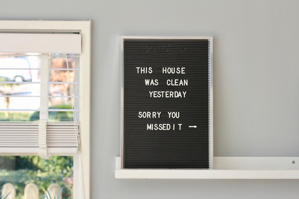 black wooden signage on white wooden floating shelf