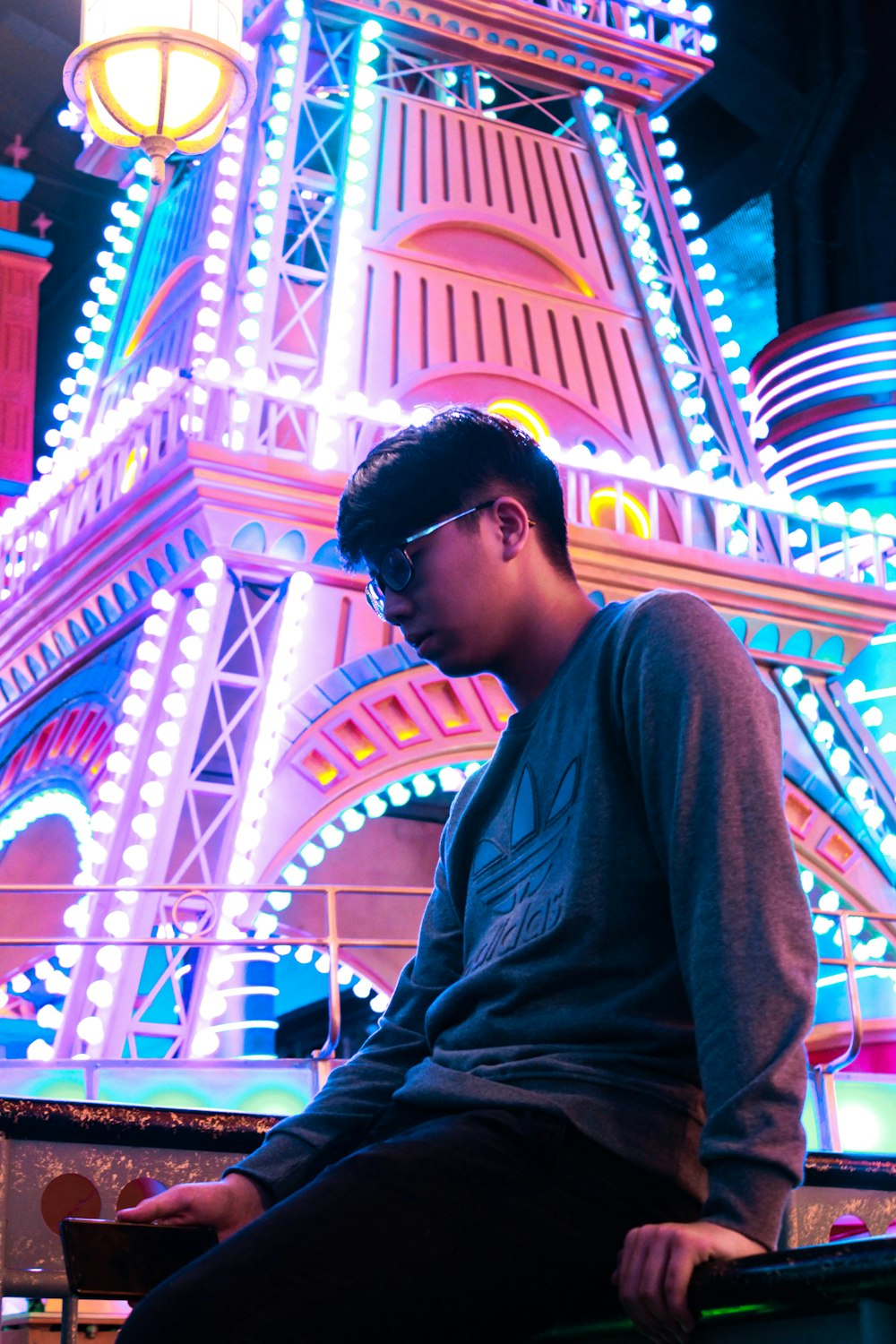 man wearing gray adidas long-sleeved shirt across lighted tower