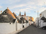 A scenic view from a car window driving through Puglia’s rolling countryside dotted with white trulli houses.