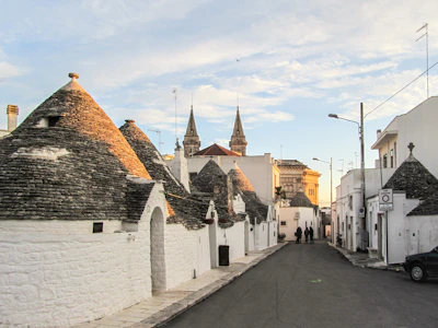 A scenic view from a car window driving through Puglia’s rolling countryside dotted with white trulli houses.