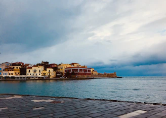 A lively Mediterranean coastal town with colorful buildings and a bright blue sea under a sunny sky.