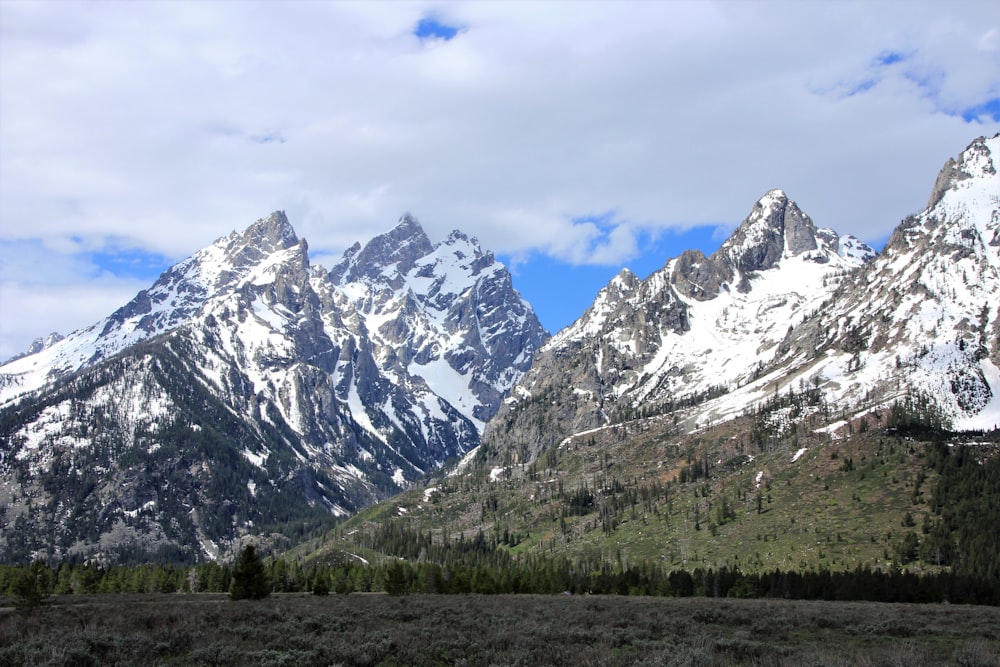 mountain range covered by snow under cloudy sky during daytime