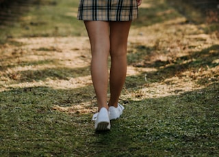 shallow focus photo of woman in white and black plaid mini skirt walking