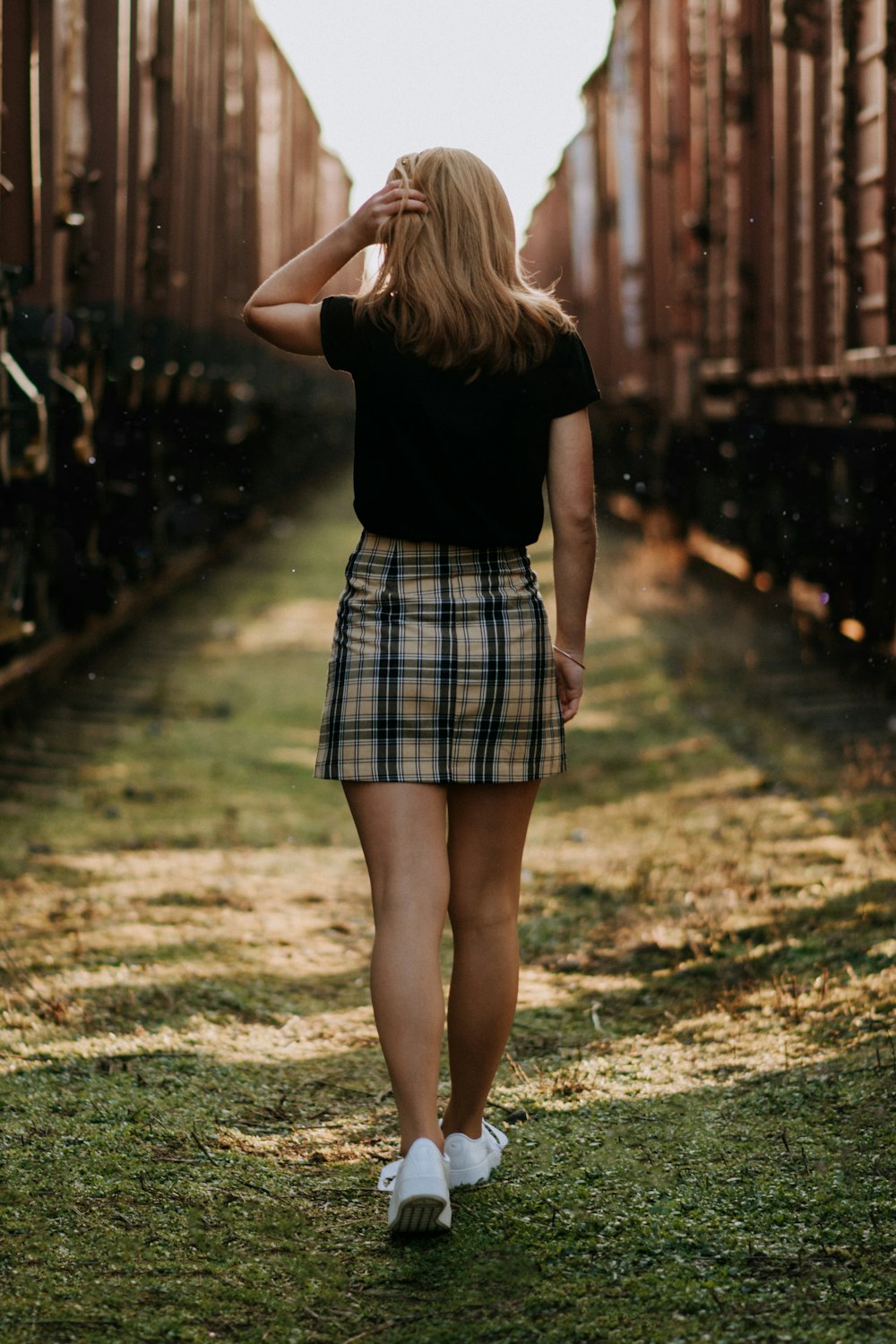 shallow focus photo of woman in white and black plaid mini skirt walking