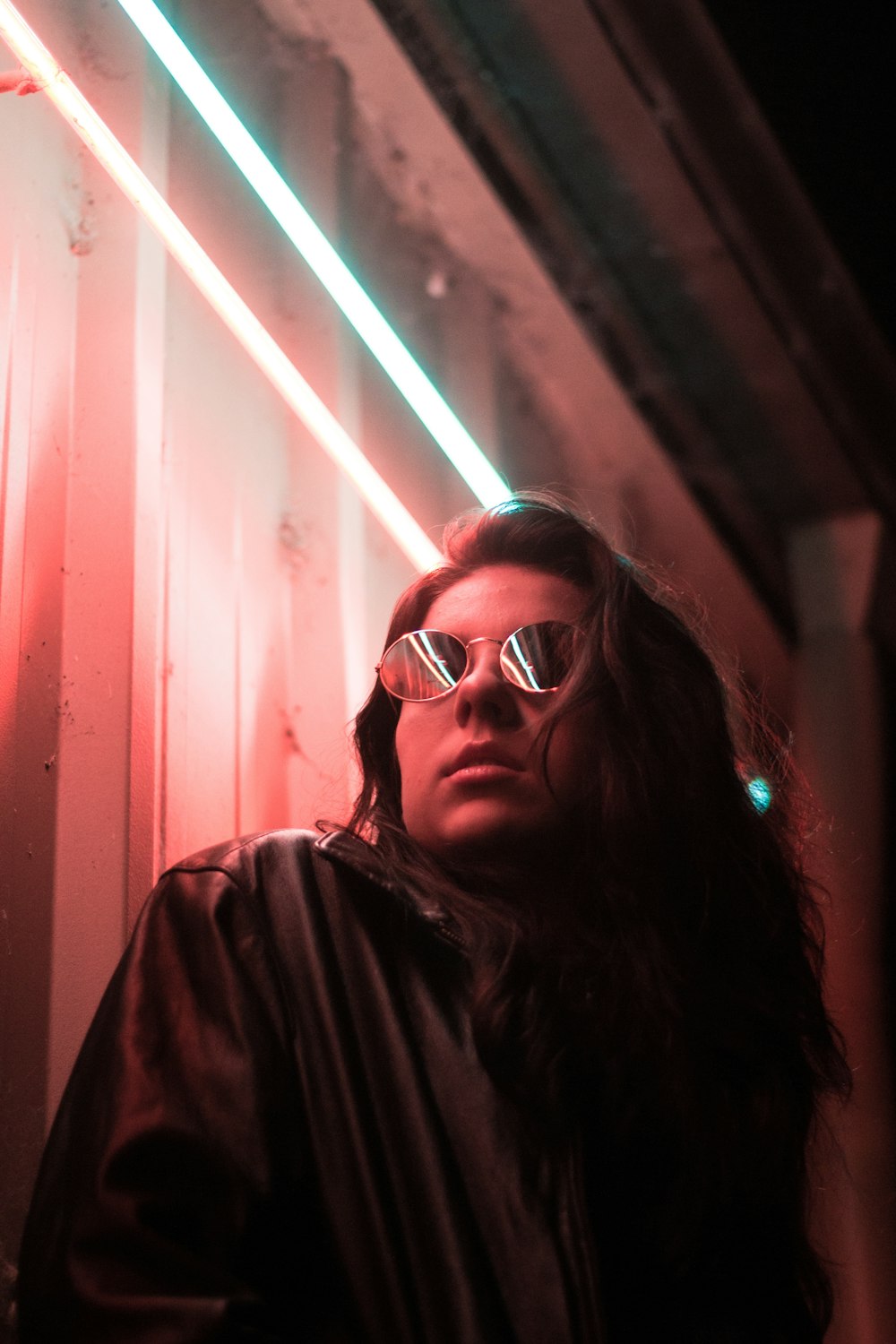 woman wearing round sunglasses leaning on glass board