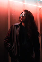 A model wearing a reflective jacket with interstellar patterns, standing under neon lights.