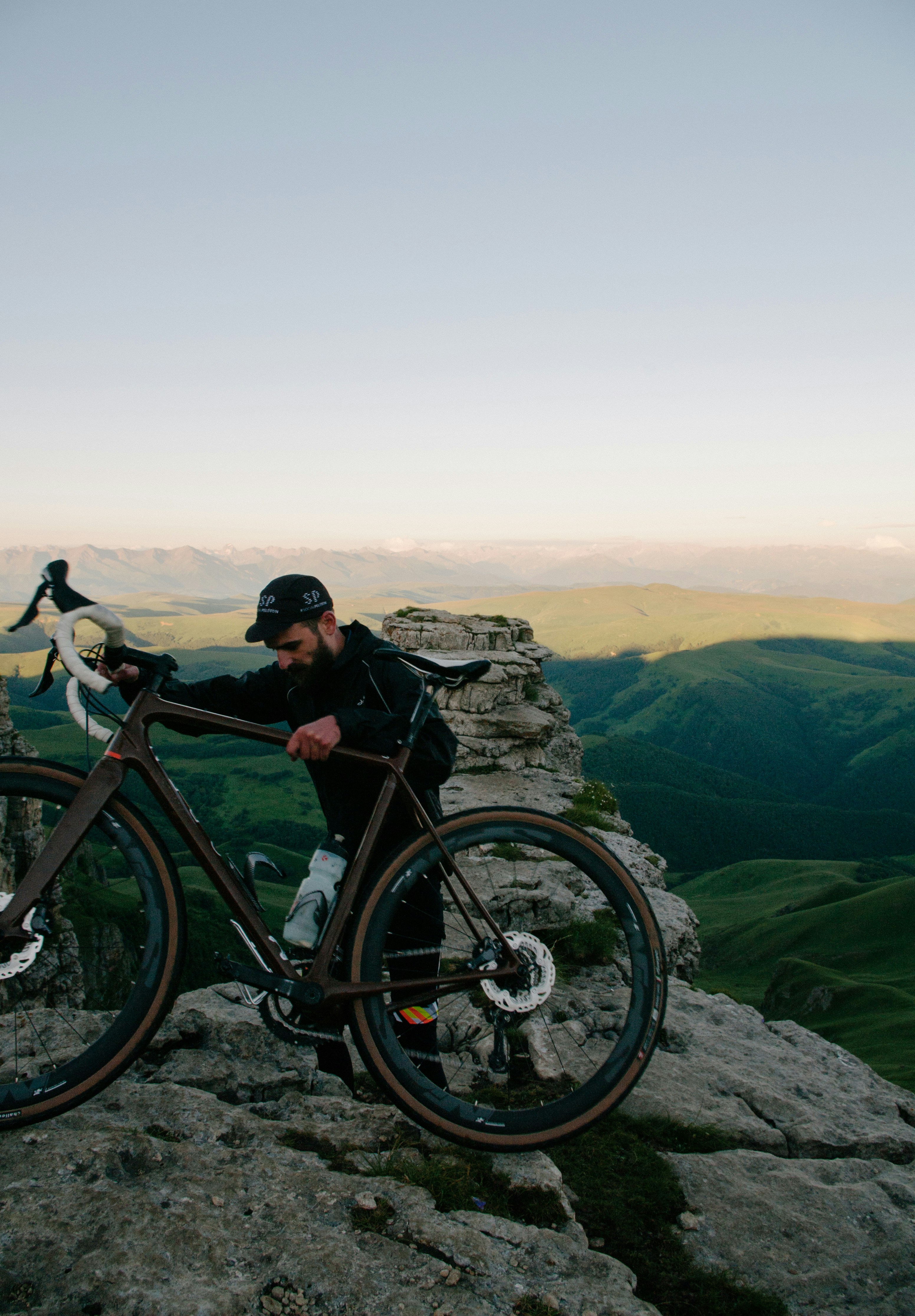 man carrying road bike at top of mountain