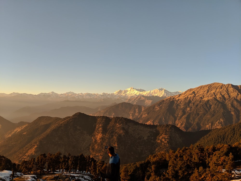 man in black and blue jacket standing infront of mountain