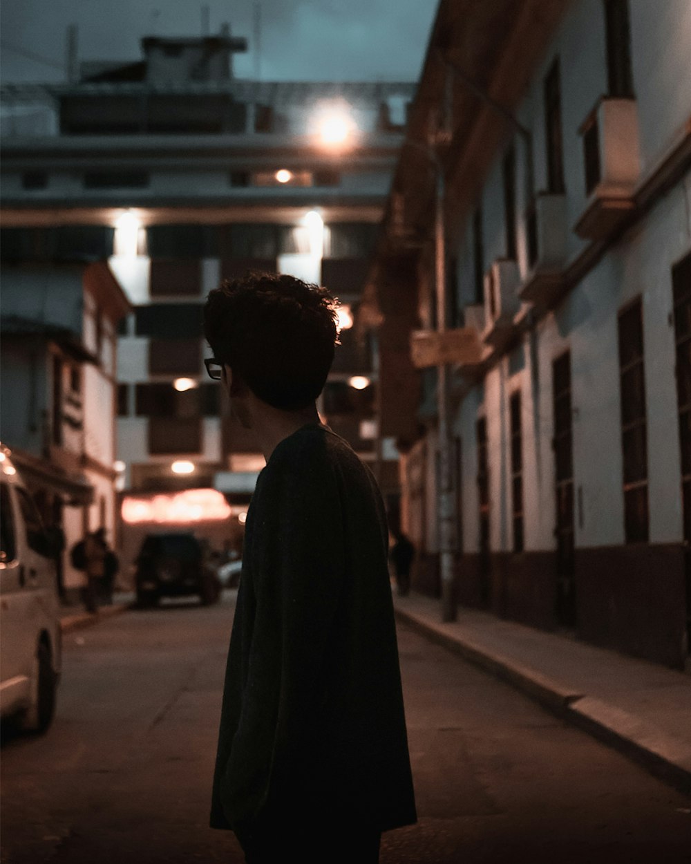 man standing in the middle of the street during nighttime