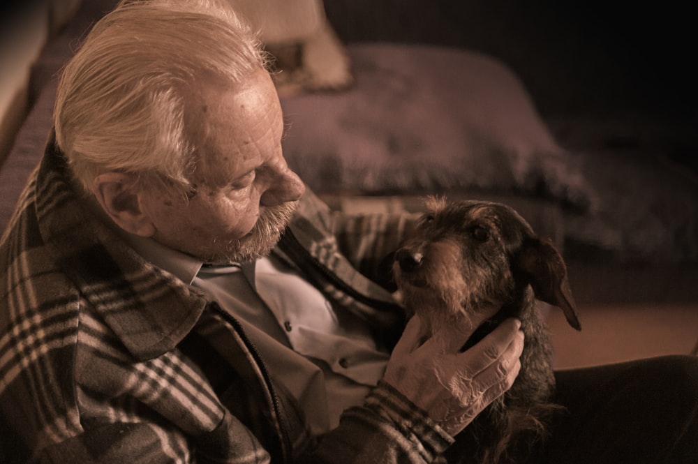 man in plaid jacket holding tan dog