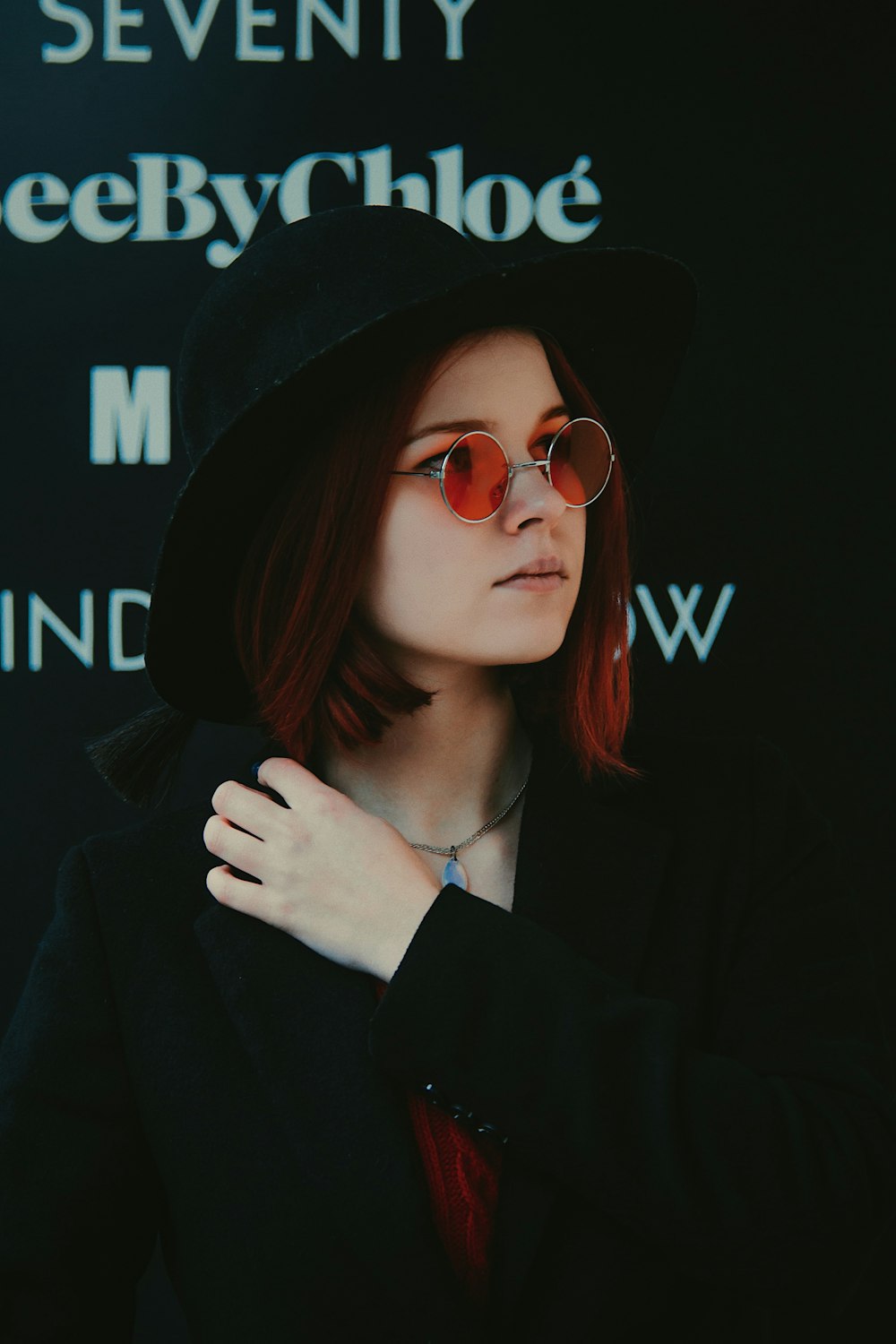 mulher no blazer preto e óculos de sol vermelhos