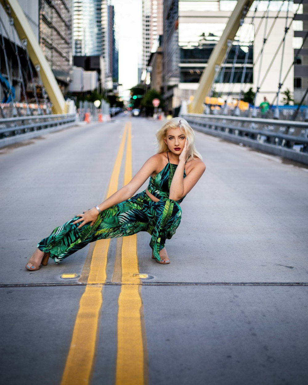 woman in green rompers squatting in middle of bridge