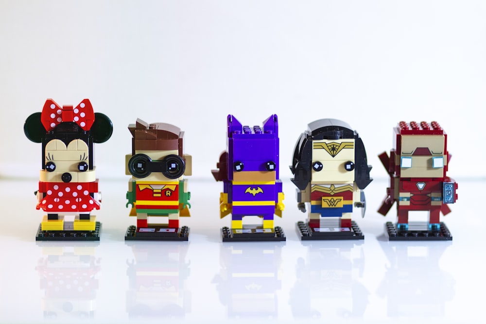 five assorted LEGO character figurines on white surface