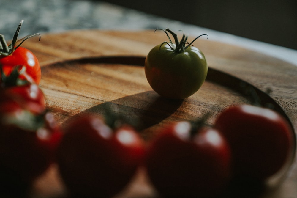 green tomato in front of red tomatoes closeup photo