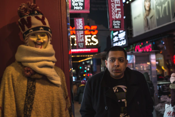 A vibrant shot of a neon-lit alleyway with a mannequin dressed in layered streetwear and a snapback hat.