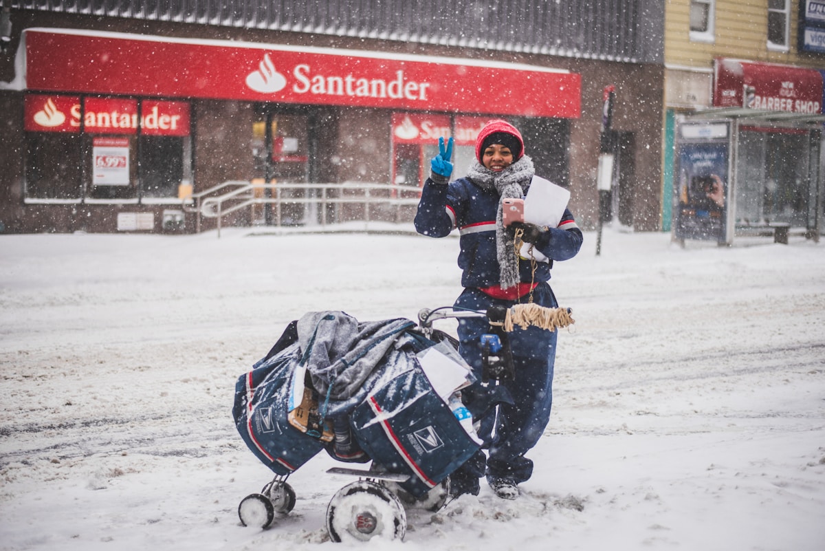 a snowy scene of a lady standing in front of Santander bank