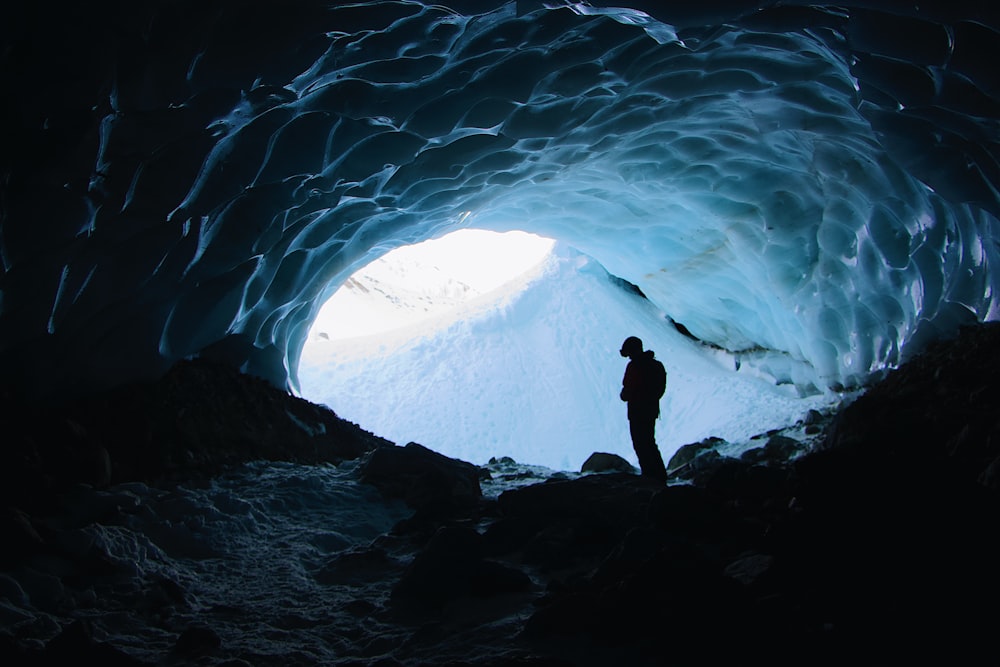 silhouette of person under frozen cave during daytime