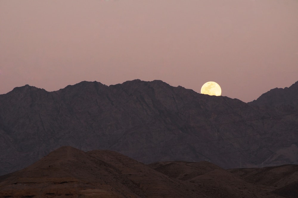 full moon over mountain ranges during daytime