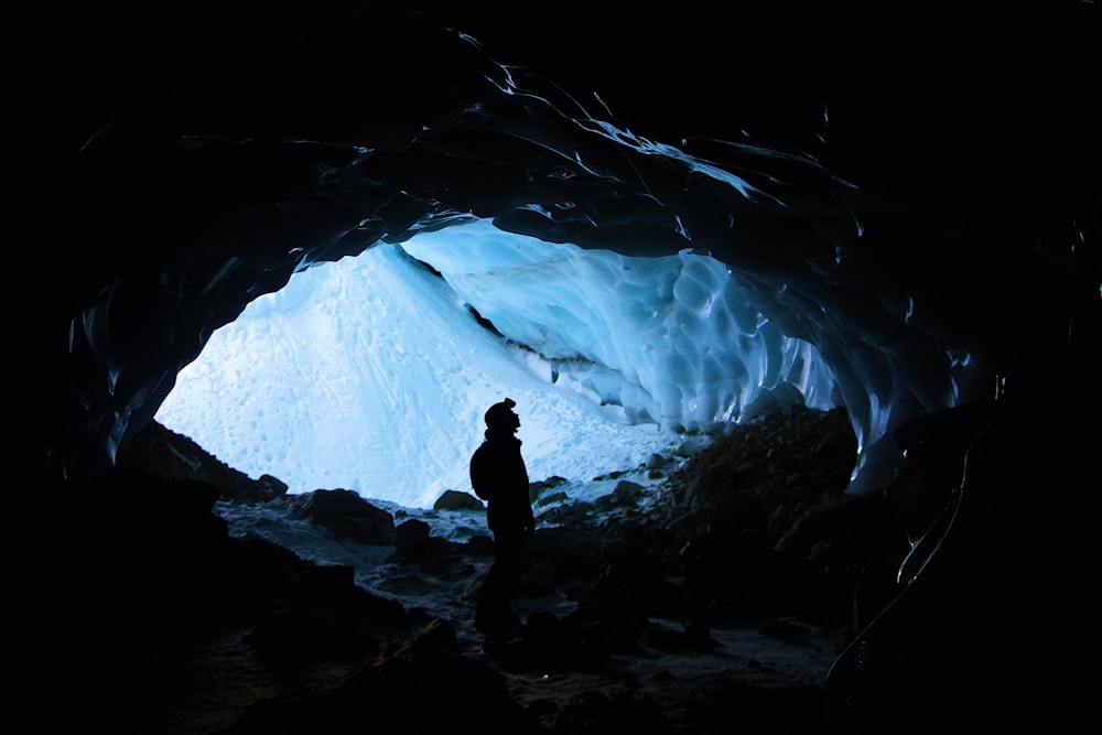 silhouette of person standing inside cave