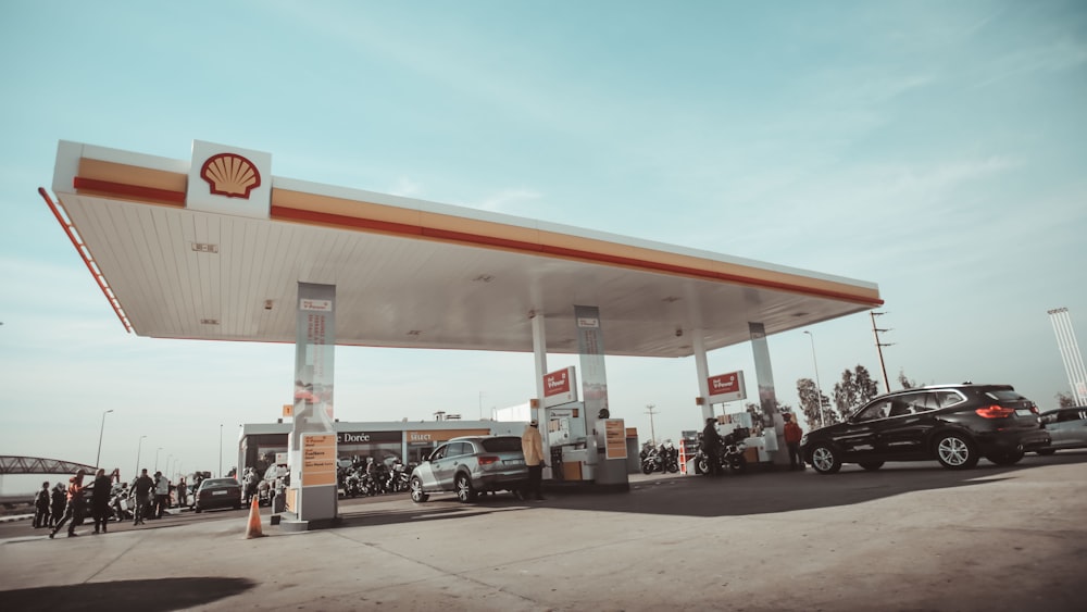 vehículos y personas en la gasolinera Shell durante el día