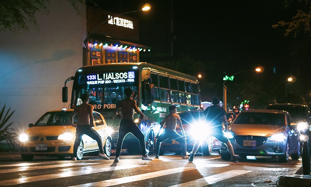 four people standing on street beside vehicles