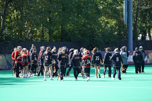 Young athletes in Michigan Firehawks jerseys sharing a high-five on the field during a sunny afternoon practice.