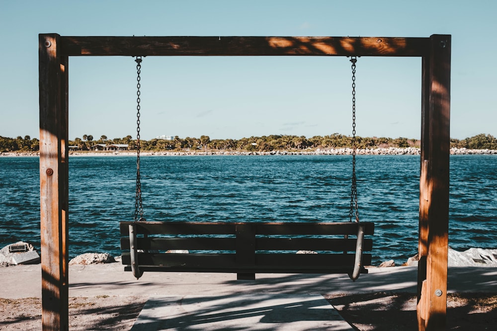 empty swing bench near body of water