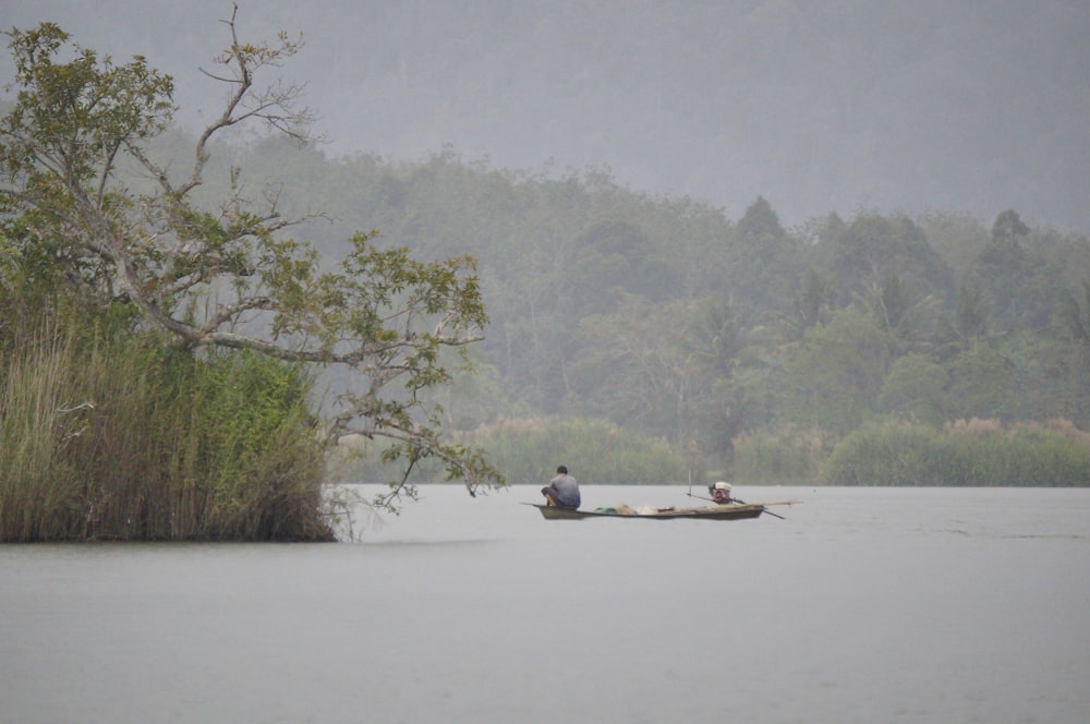 person riding canoe on calm body of water