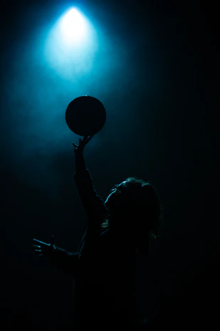 Close-up shot of a basketball spinning on a player's fingertip under bright gym lights.