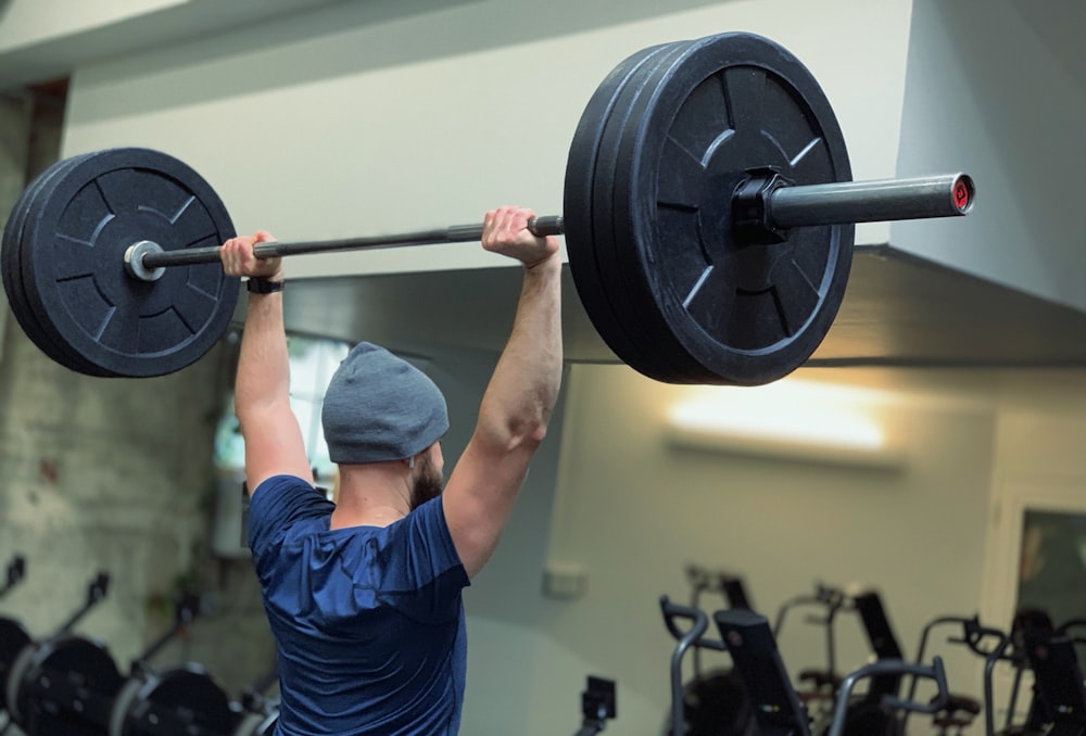 Mann hebt Langhantel im Fitnessstudio