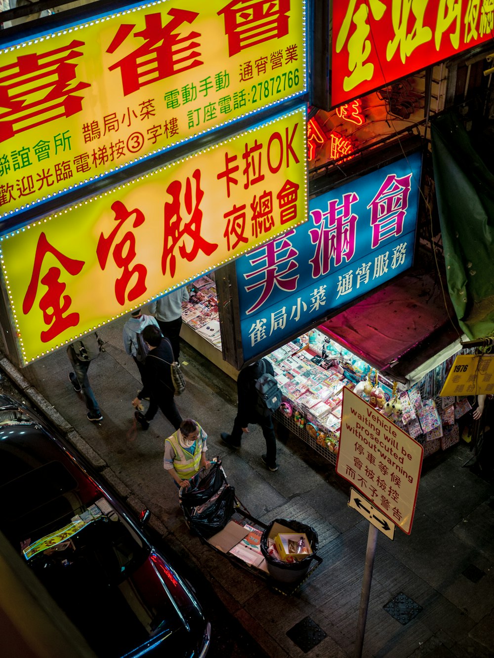 people walking on sidewalk under lighted store signs