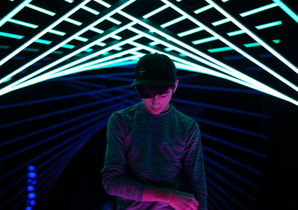 man in grey long sleeved shirt standing in room with neon ssigns