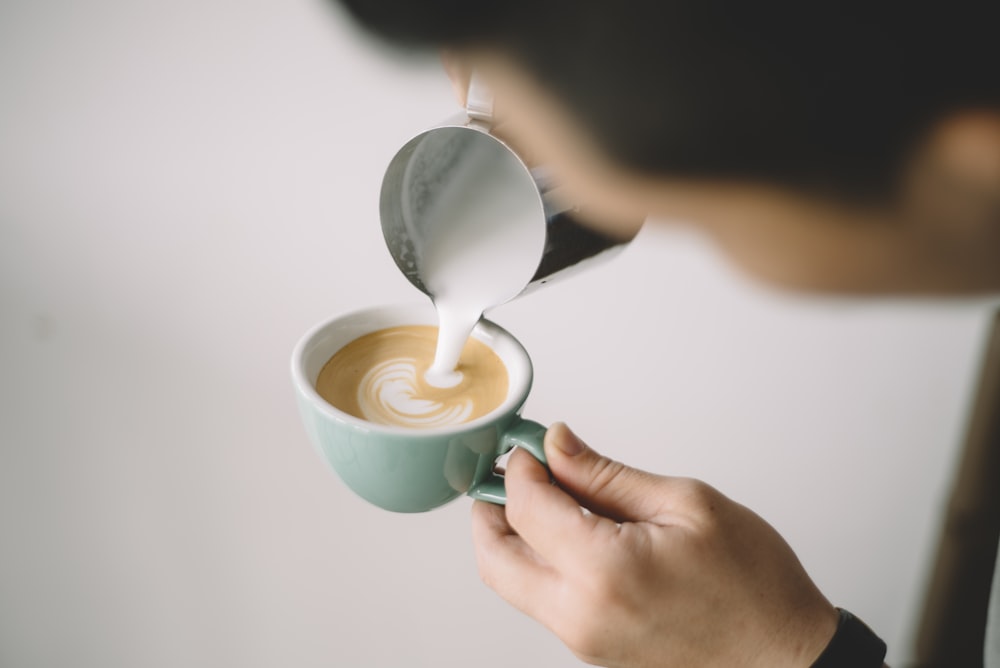 person pouring coffee on white ceramic mug