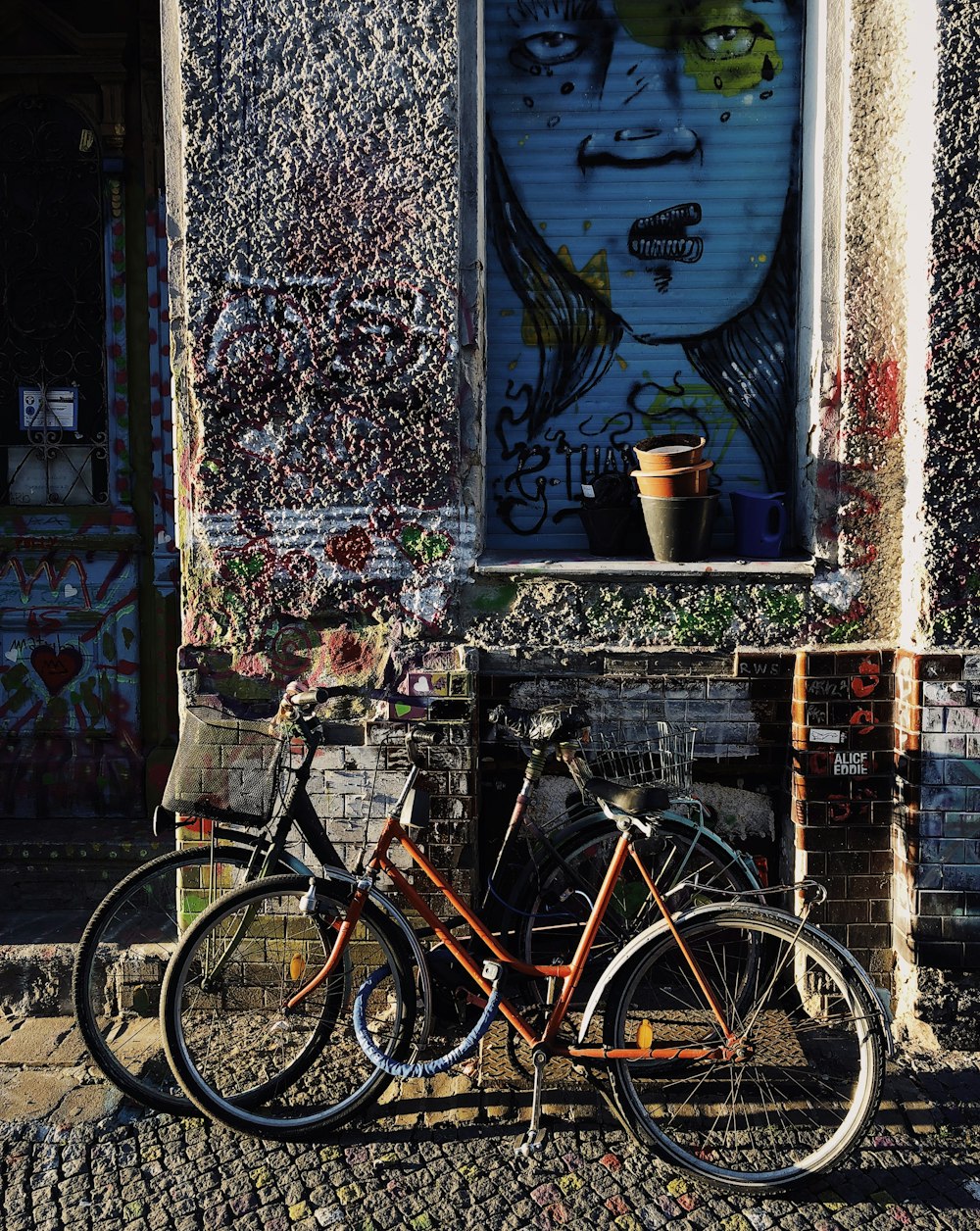 three bicycles parked near floral painted building at daytime