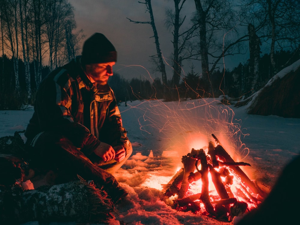 man sitting beside fire