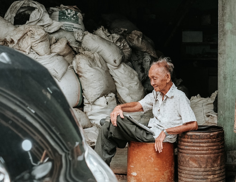 man sitting on brown metal barrel