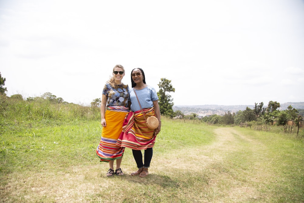 two women standing near green grass field